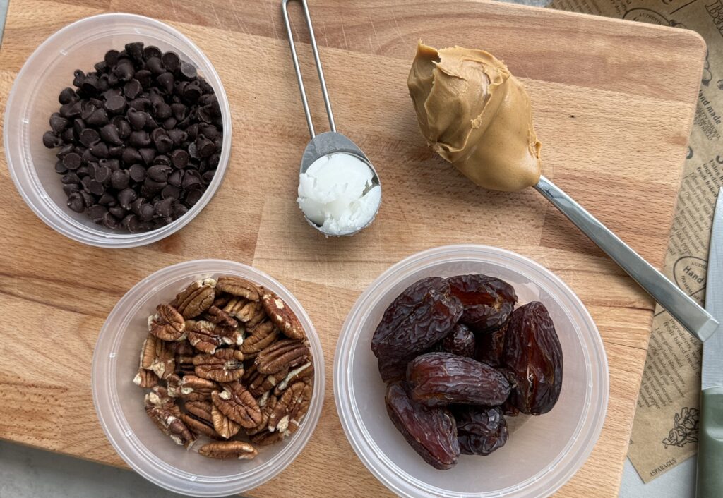 chocolate pecan turtle clusters recipe - dark chocolate, coconut oil, pecans, dates, creamy peanut butter, set out on cutting board