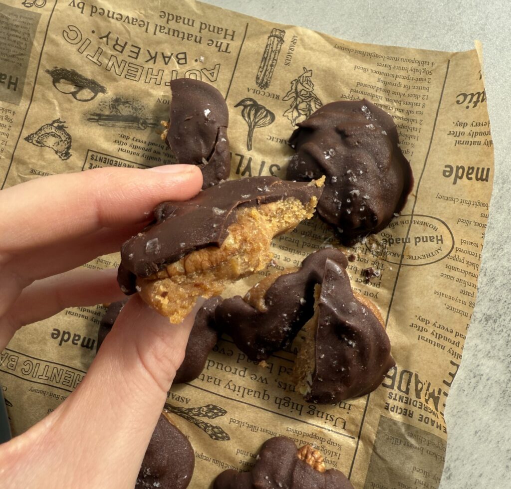 chocolate pecan turtle clusters recipe - holding turtles candy to show date caramel and pecan inside