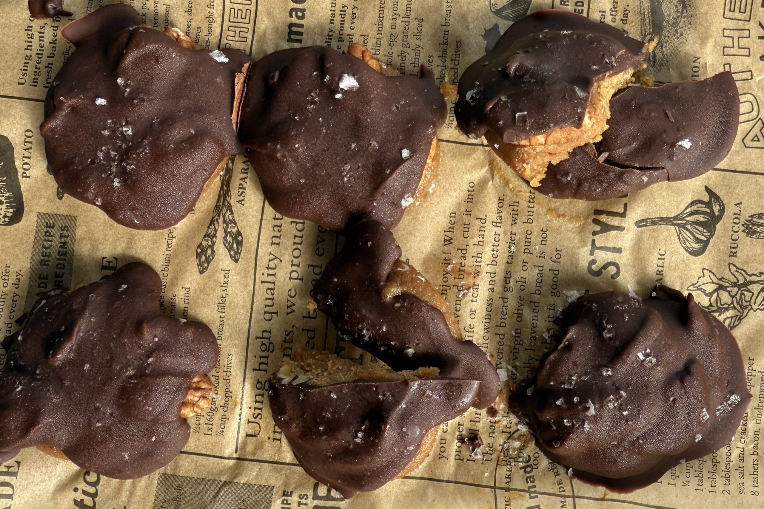 homemade turtles with date caramel, pecans, and chocolate on baking sheet